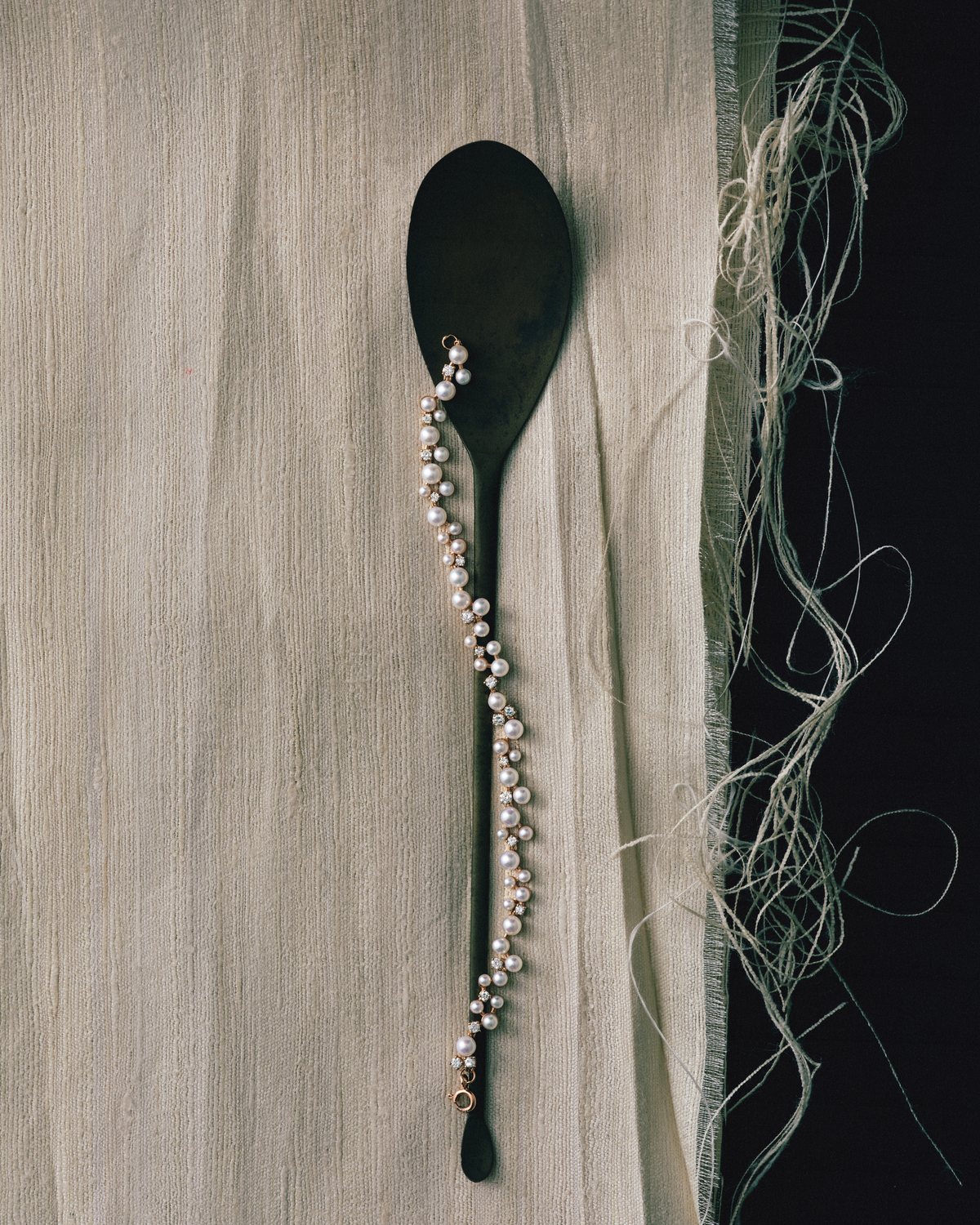 Pearl Bracelet on a wooden spoon over raw silk