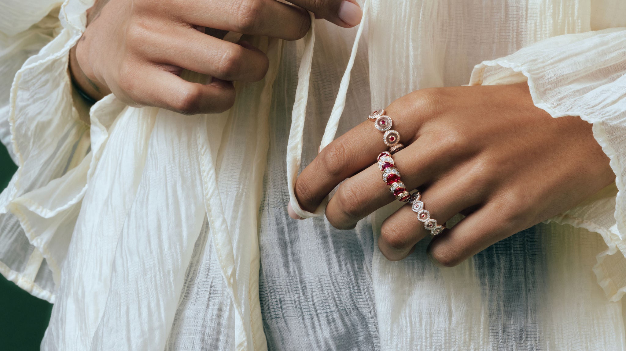 Hands wearing the Ruby Circle Eternity, Ruby Crescent and Crystal Prisme rings