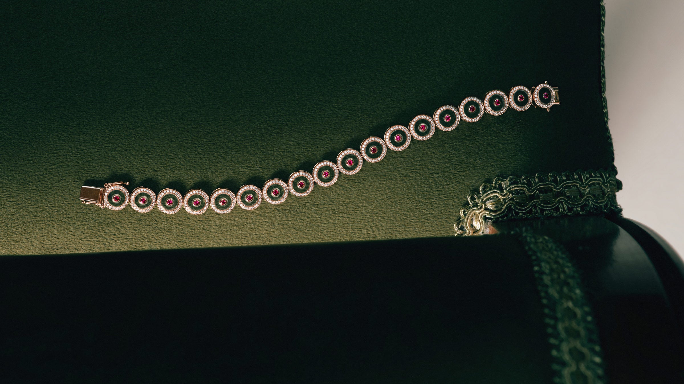 Ruby Circle Tennis Bracelet on a green velvet sofa