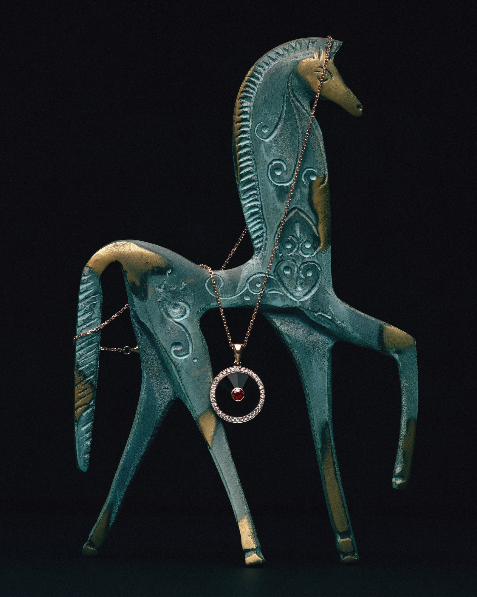 Ruby Circle Pendant in 18K rose gold on an enamelled horse sculpture